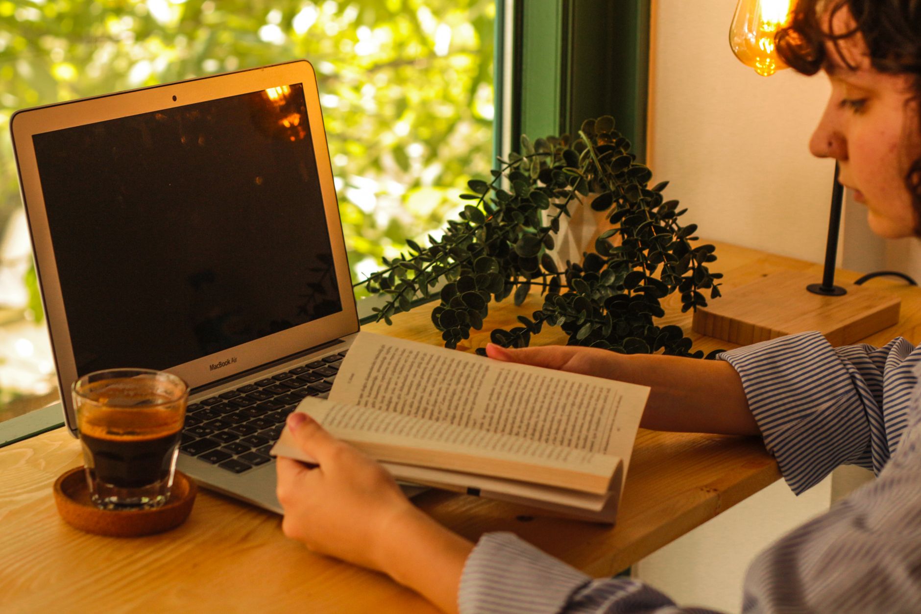 Un intérieur chaleureux avec un ordinateur portable, un café et un livre, espace de travail cocooning.